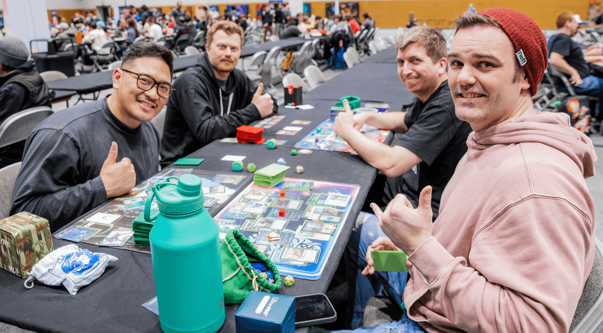 People Playing Magic at LDXP, looking at the camera and giving thumbs-up